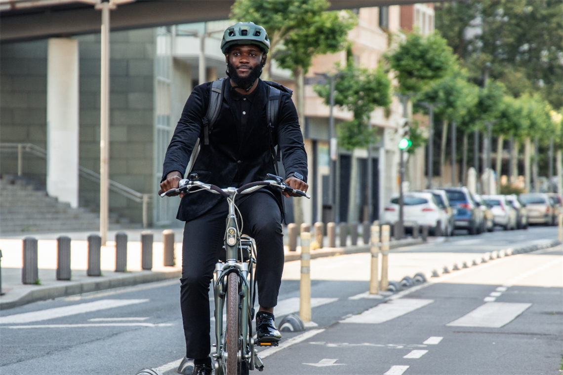 A man riding bicycle with helmet and business attire