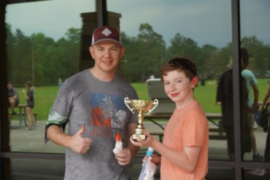 Photo of father and son holding a small gold trophy