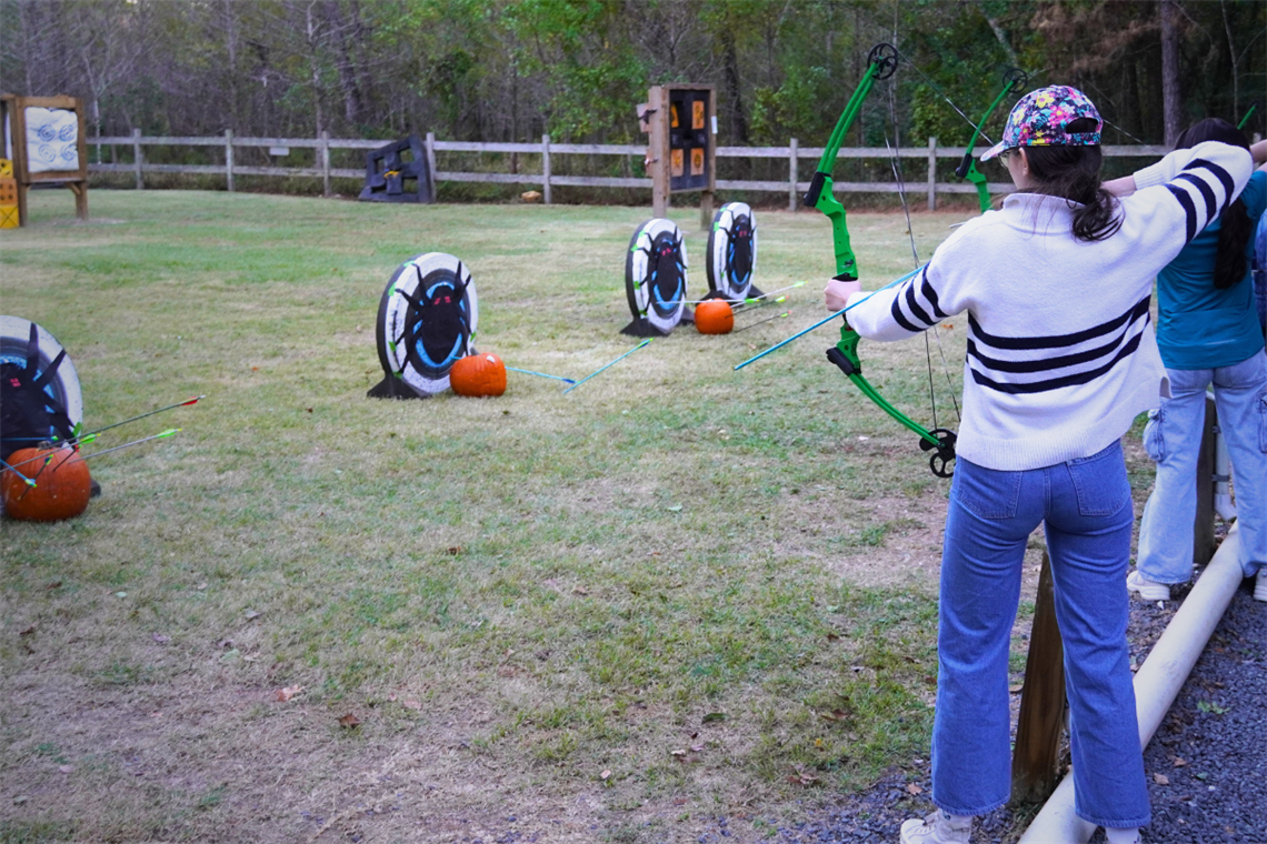 A person with a bow in hand shooting target outdoors