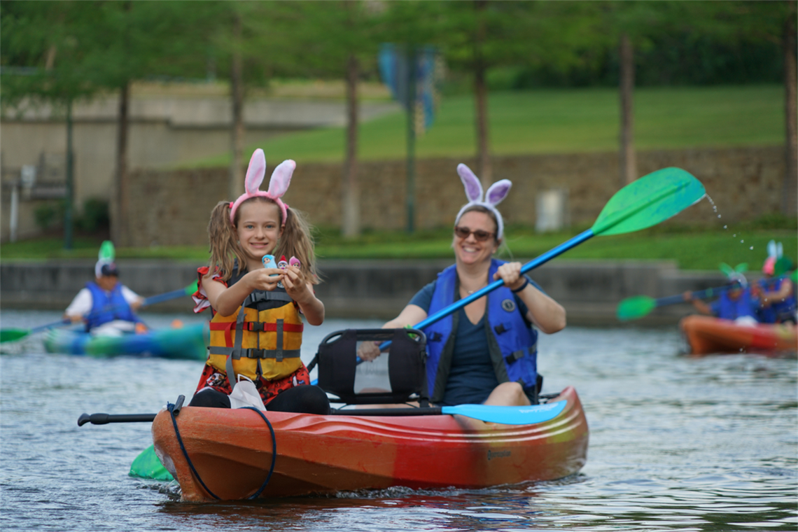 Adult and child in a kayak wearing bunny ear headbands