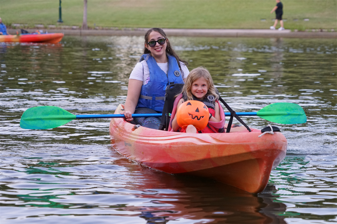 Mother and daughter in a tandem kayak floating on the water.