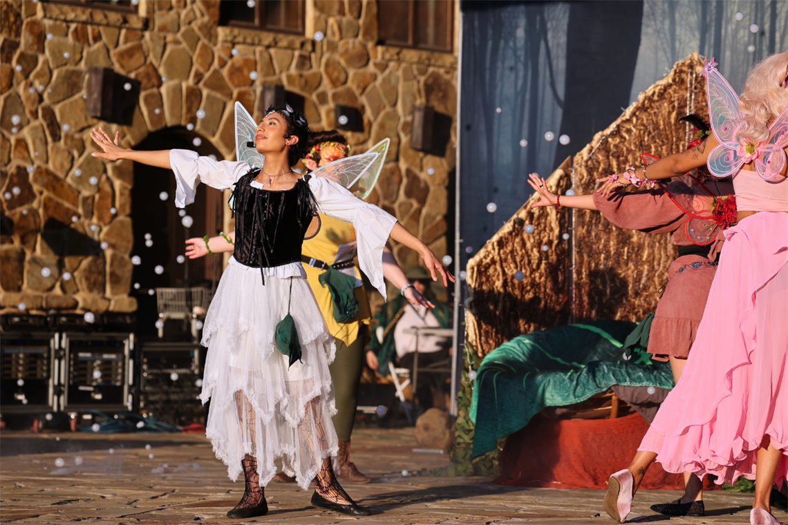 A woman dressed in a Renaissance-era costume on a stage with other performers