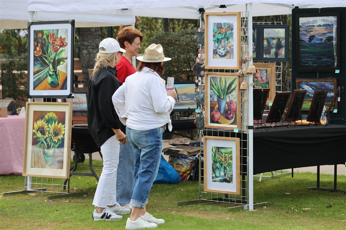 Photo of festival attendees looking at painted art displayed 