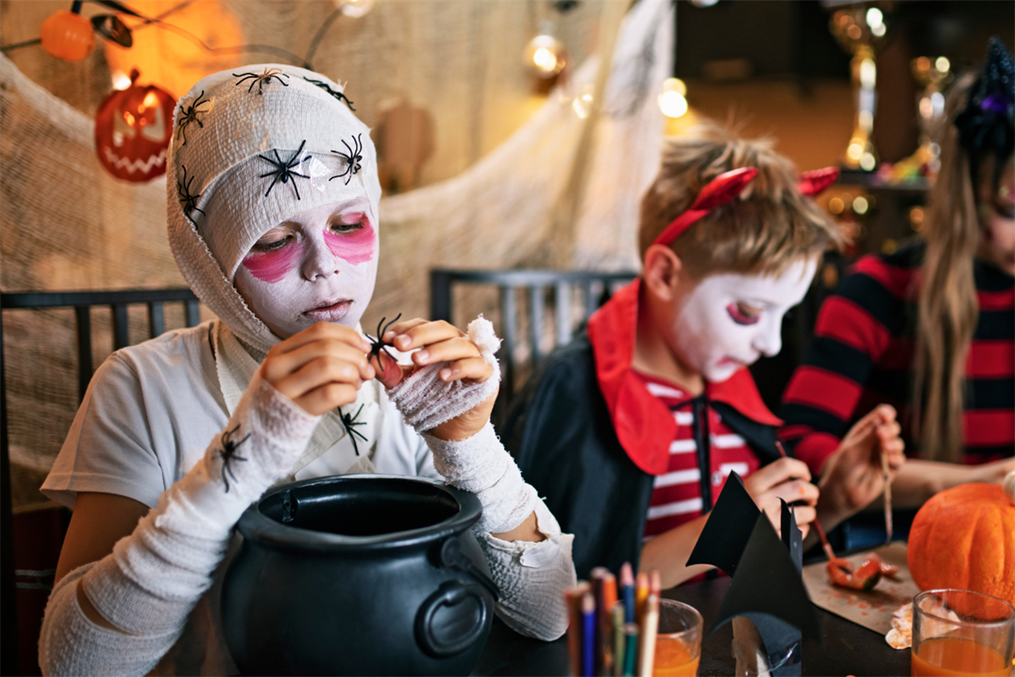 Children in costumes looking at candy and making crafts