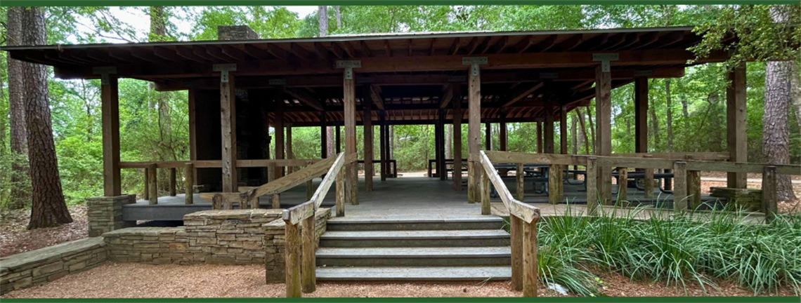 A large wooden pavilion in a wooded area