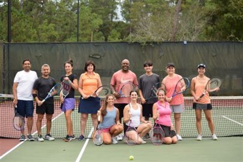 People-posing-with-tennis-rackets-on-tennis-court.jpg