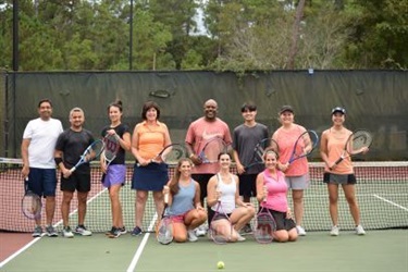 People-posing-with-tennis-rackets-on-tennis-court.jpg